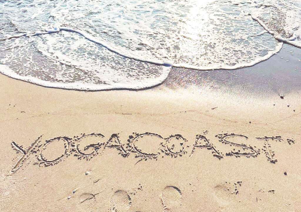 Yogacoast Erfahrungen. Yogacoast mit Schriftzug in den Sand geschrieben