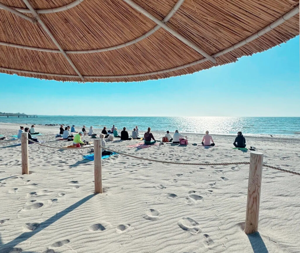 Gruppe Menschen meditiert am Strand
