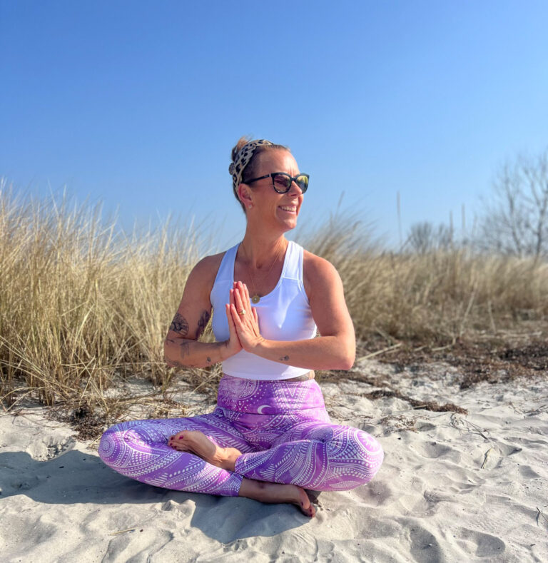 Frau meditiert im Lotussitz am Strand
