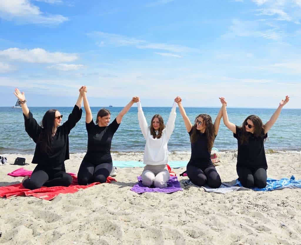 JGA Yoga Ostsee - Junggesellinnenabschied am Strand mit Freundinnen. 5 Frauen am Ostsee Strand, die sich an den Händen halten