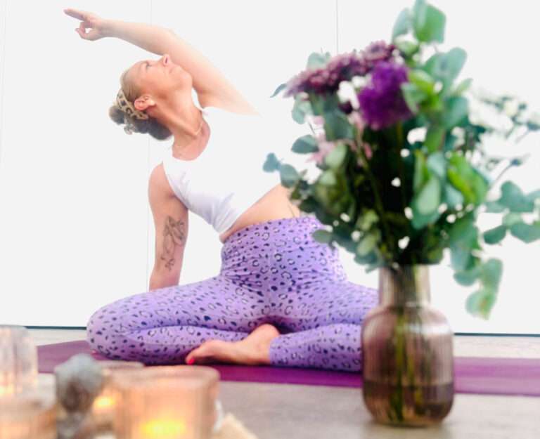 Yogalehrerin auf einer Yogamatte mit einer Blumenvase