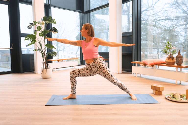 Yoga Lehrerin in der Yogaübung "zweiter Krieger"