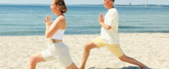 Yoga Retreat an der Ostsee. Eine Frau und ein Mann in der Krieger-Pose mit den Händen vor der Brust (Anjali Mudra) am Strand beim Yoga Retreat an der Ostsee.