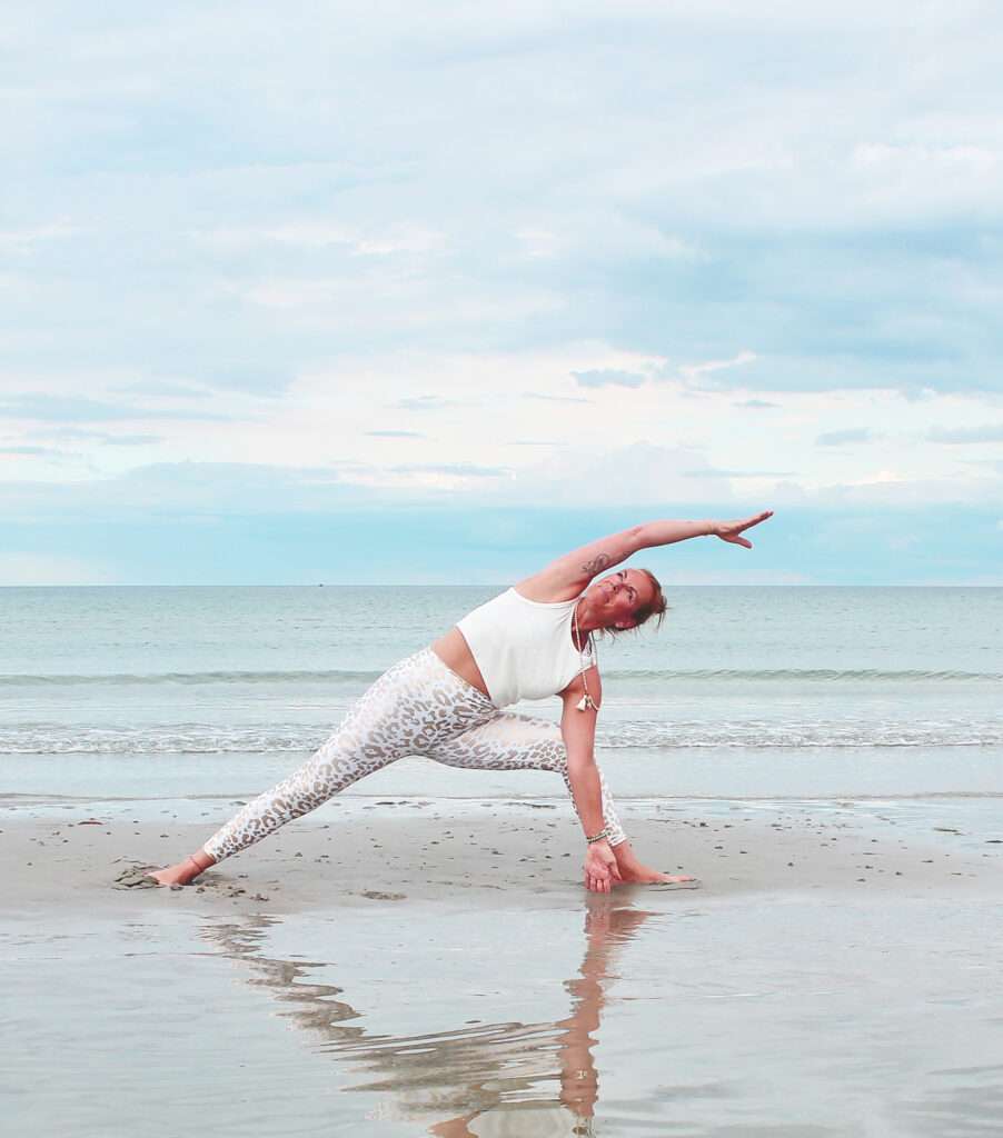 Yoga an der Ostsee. Yoga-Lehrerin Tina praktiziert Strandyoga an der Ostsee in Scharbeutz, im Hintergrund das Meer und die Weite der Lübecker Bucht.