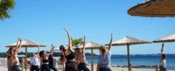 OM The Beach - Yoga Teilnehmer am Strand in Scharbeutz, Haffkrug mit Strandschirmen.
